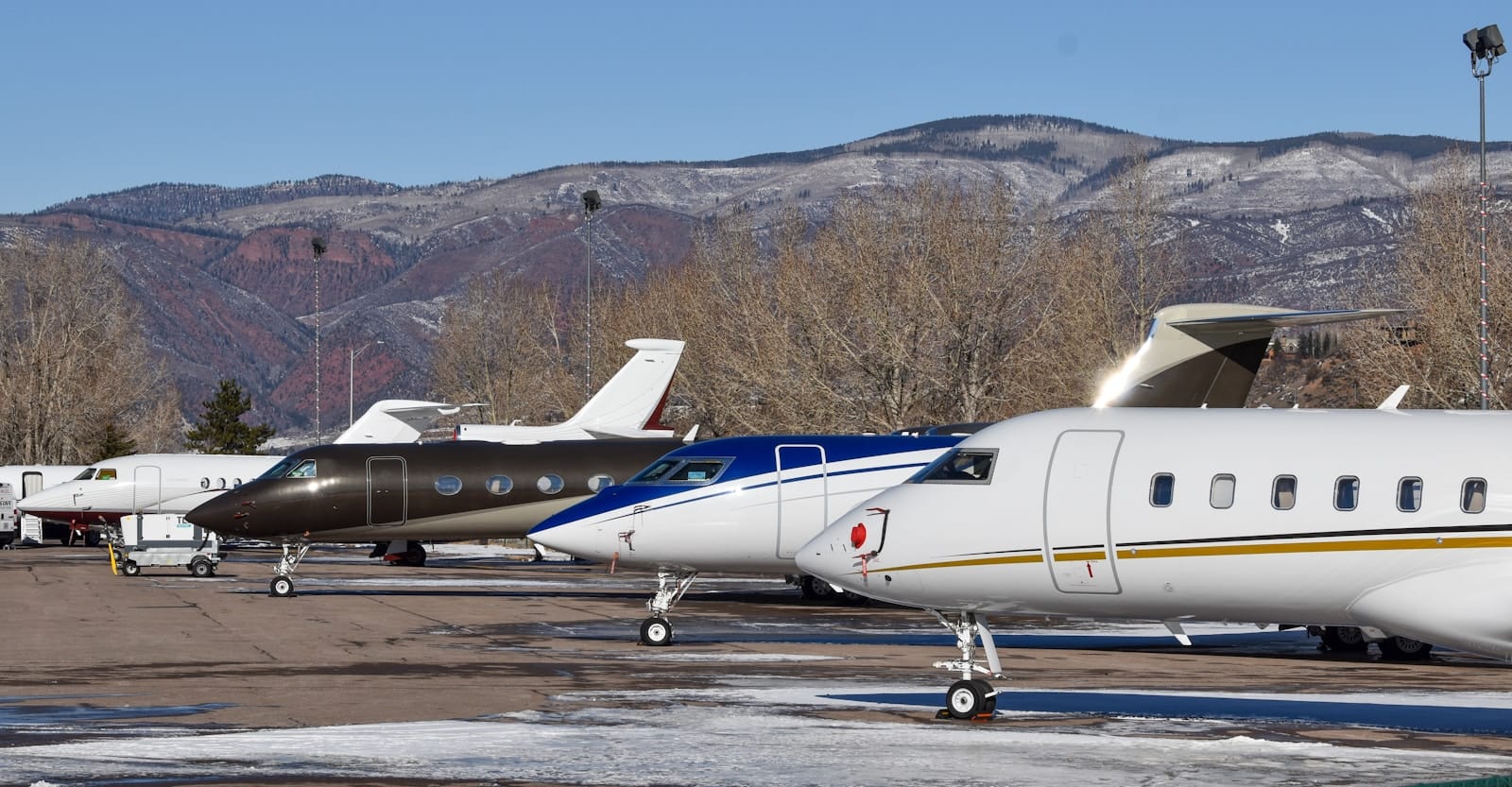 Private jets parked on the Aspen ramp against snow-dusted Colorado peaks