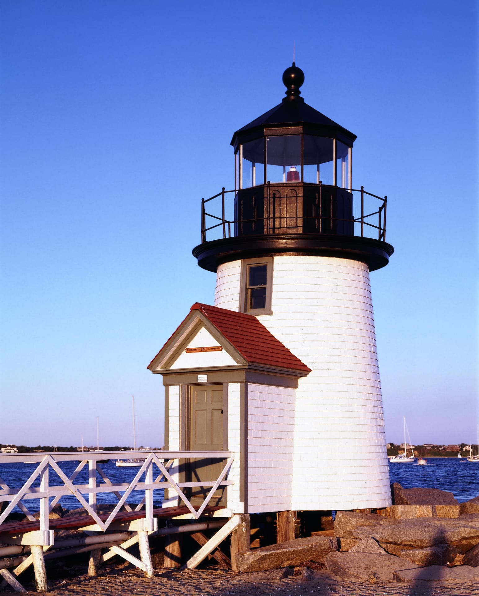 Brant Point Lighthouse on Nantucket harbor with sailboats behind it