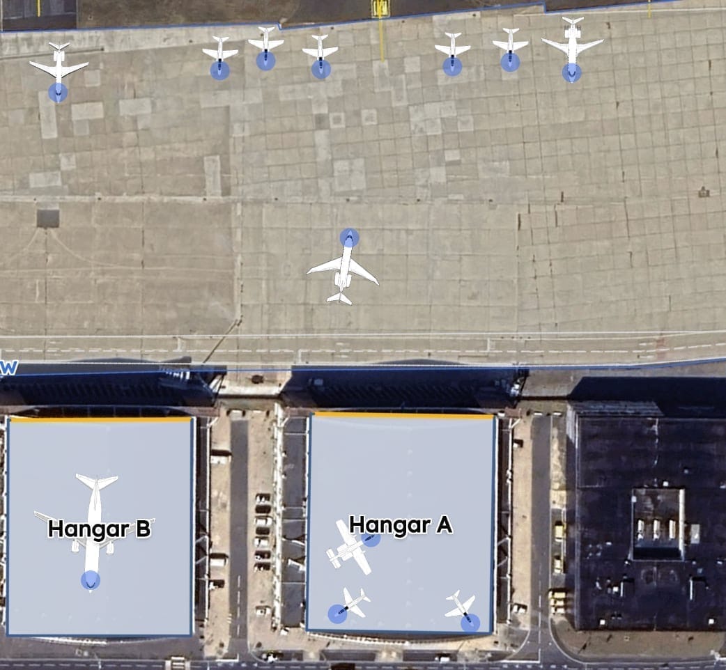 Aircraft mid-drag from one hangar onto a neighboring ramp