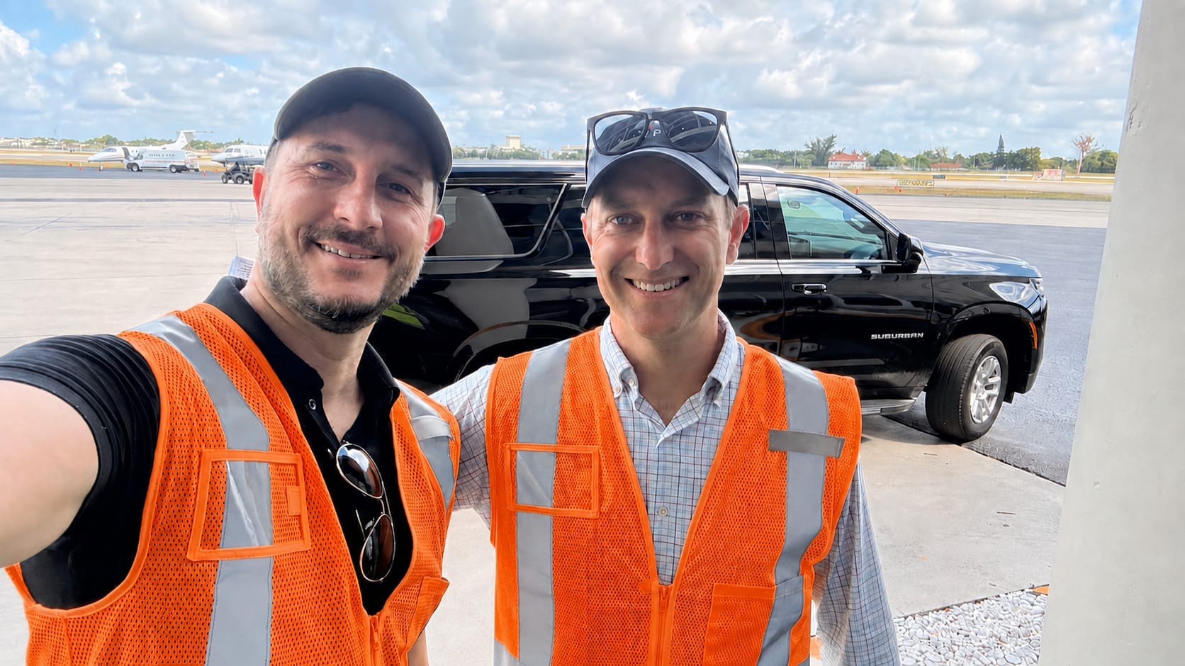 Two members of the AirPlx team in high-visibility vests on a customer ramp, with a vehicle, a business jet and a fuel truck behind them